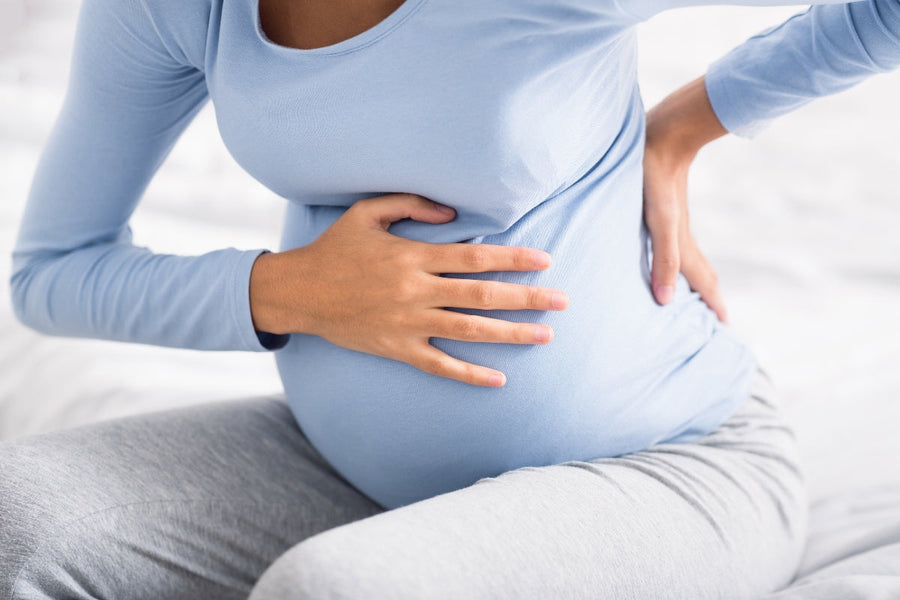 Pregnant woman sitting down trying to relieve back pain during pregnancy