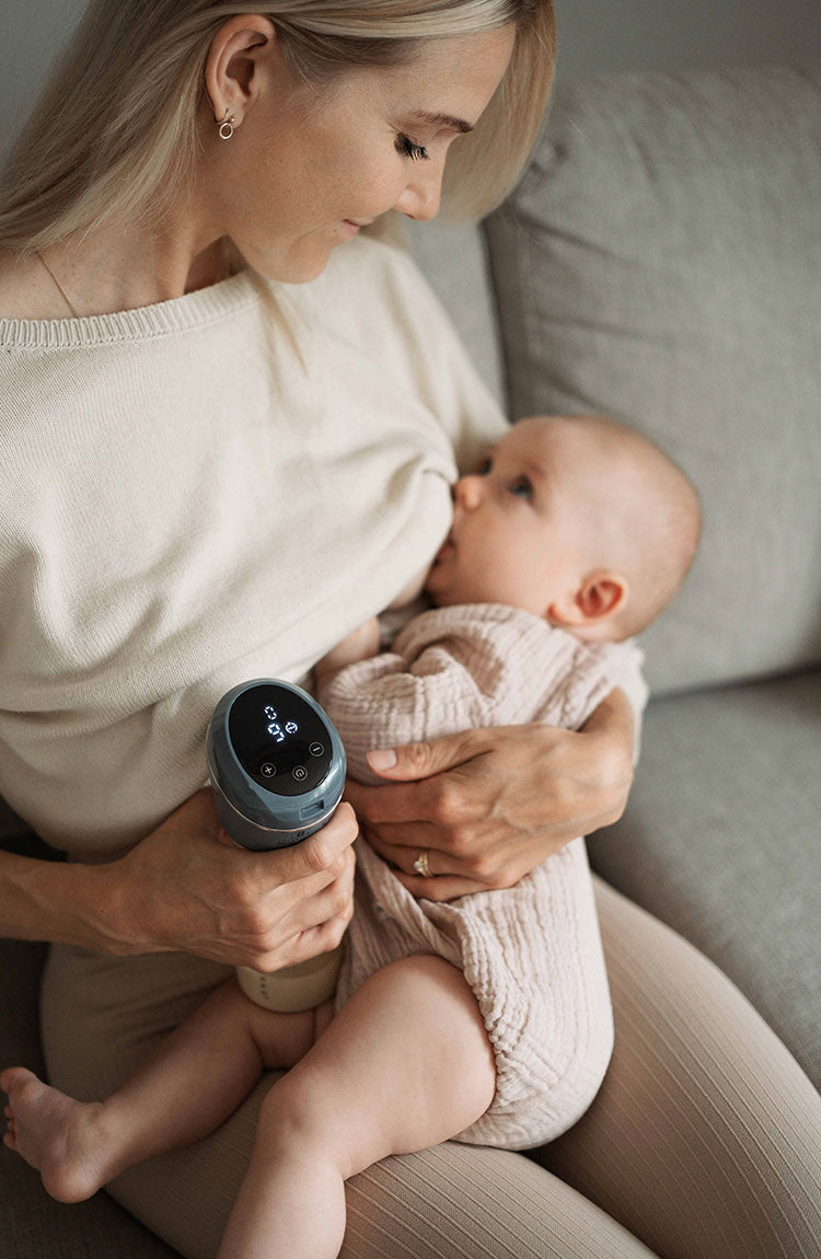 manual breastfeeding mum with a baby while holding a breast pump
