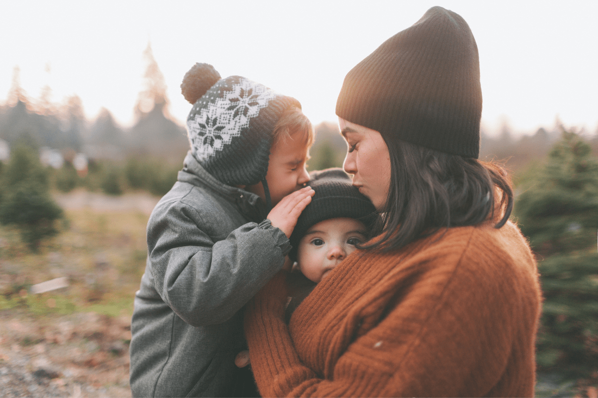 A mom is hugging and kissing her kids