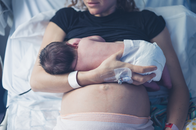 a mother breastfeeding a baby in a hospital bed after a C-section