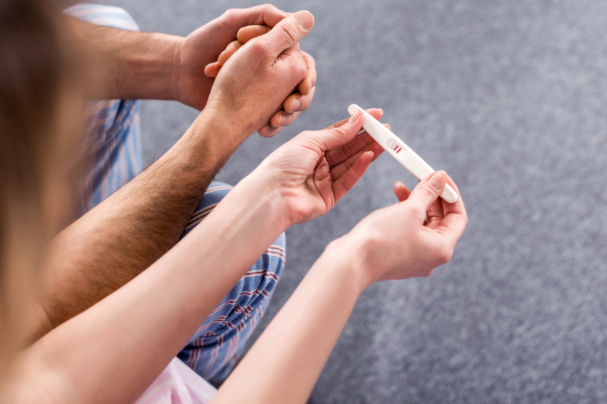 a man and a woman holding a positive pregnancy test