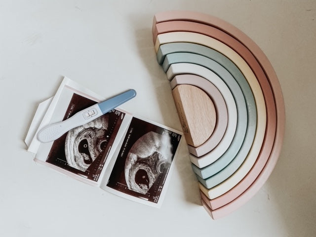 Ultrasound pictures, a pregnancy test, and a wooden rainbow toy
