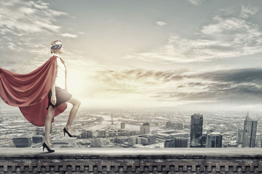 A superhero woman wearing a cloak and a mask, viewing the city skyline from above