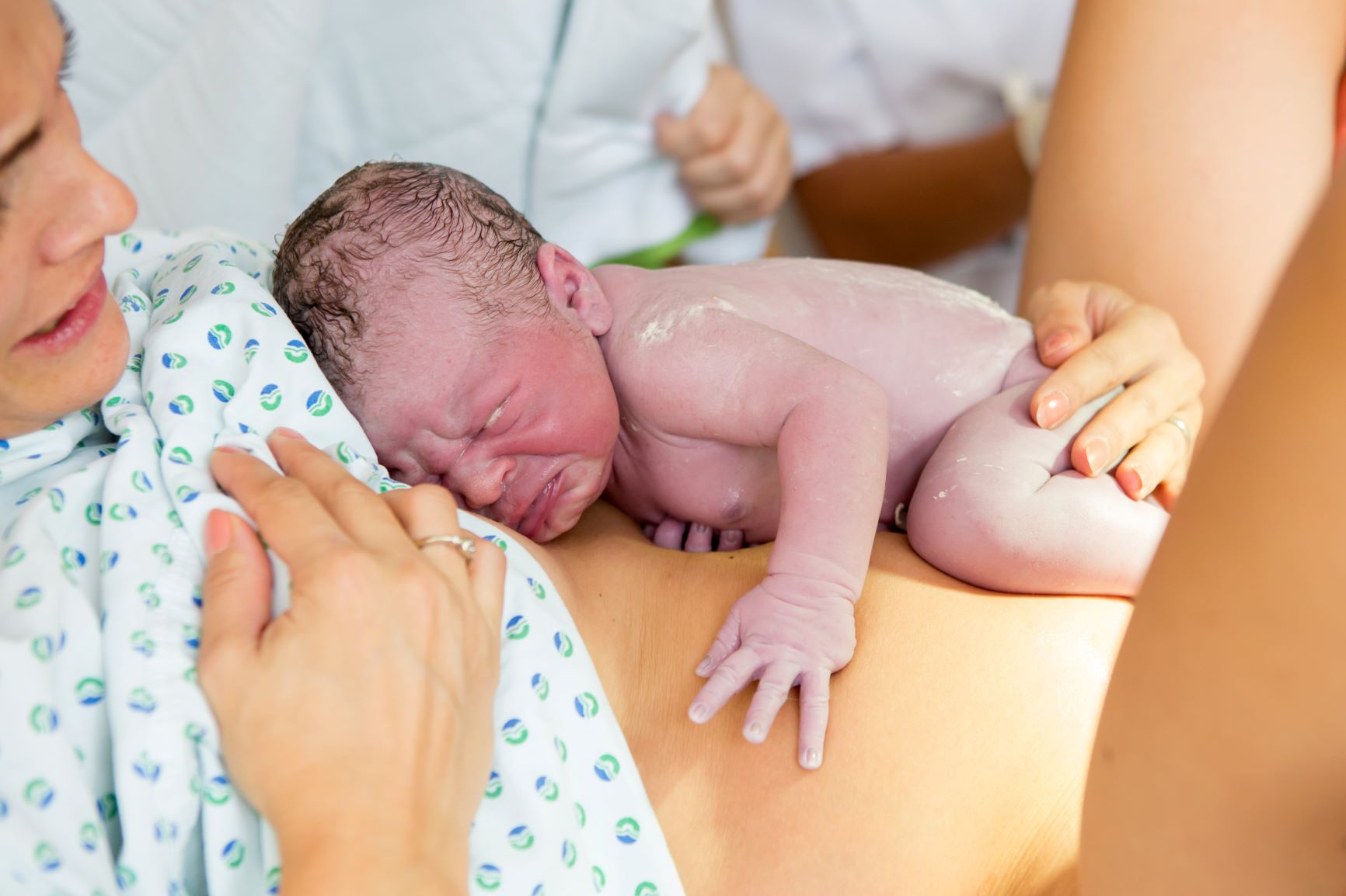 A newborn baby lying on her mother's stomach in the hospital after labor