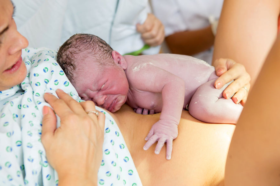 A newborn baby lying on her mother's stomach in the hospital after labor
