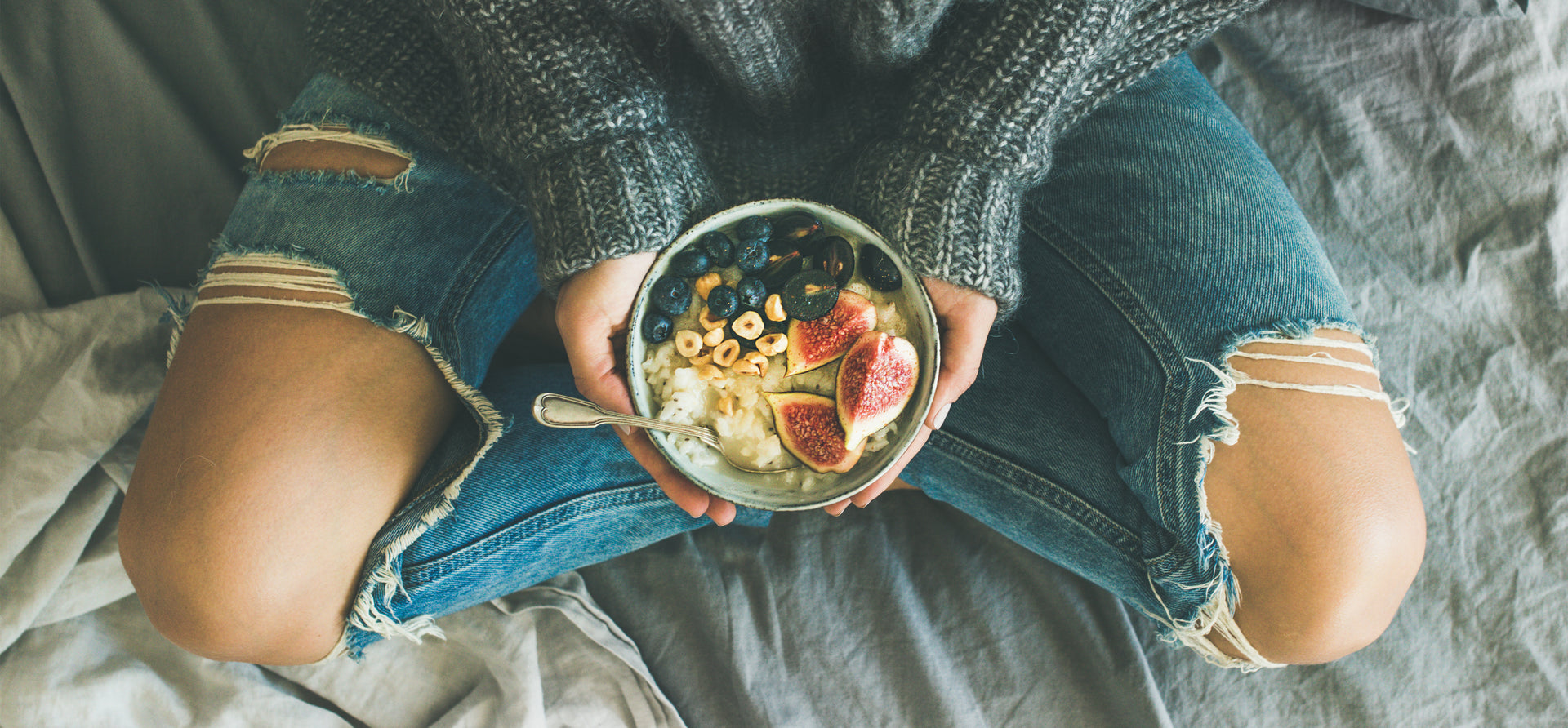 Postpartum tired woman in ribbed jeans holding a bowl of nutrient rich food