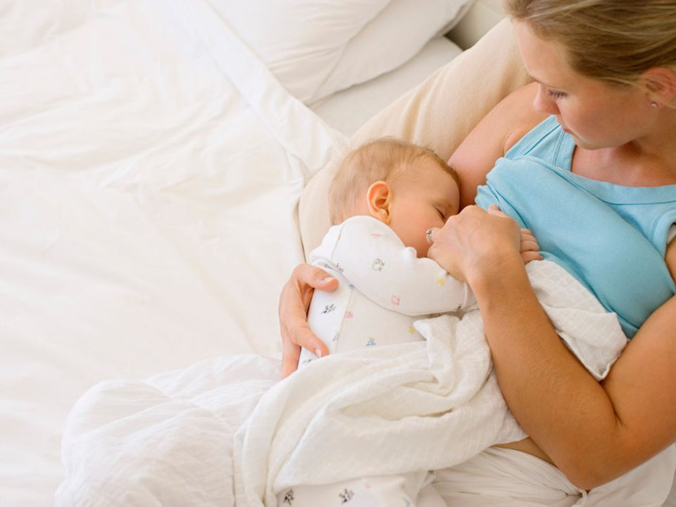 A baby peacefully nursing and drinking breast milk directly from its mother's breast