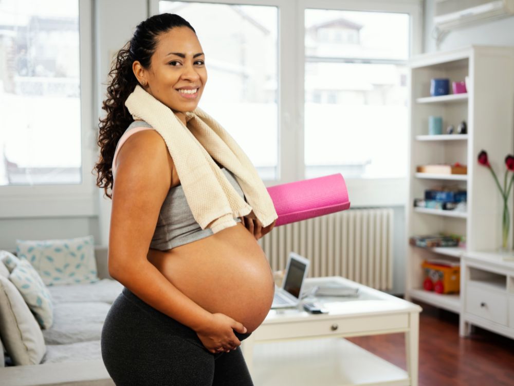 A smiling pregnant woman doing exercises to stay active during pregnancy