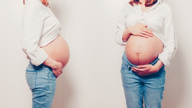  Pregnant woman holding her stomach from two different ancles wondering what bodily changes can you expect during pregnancy