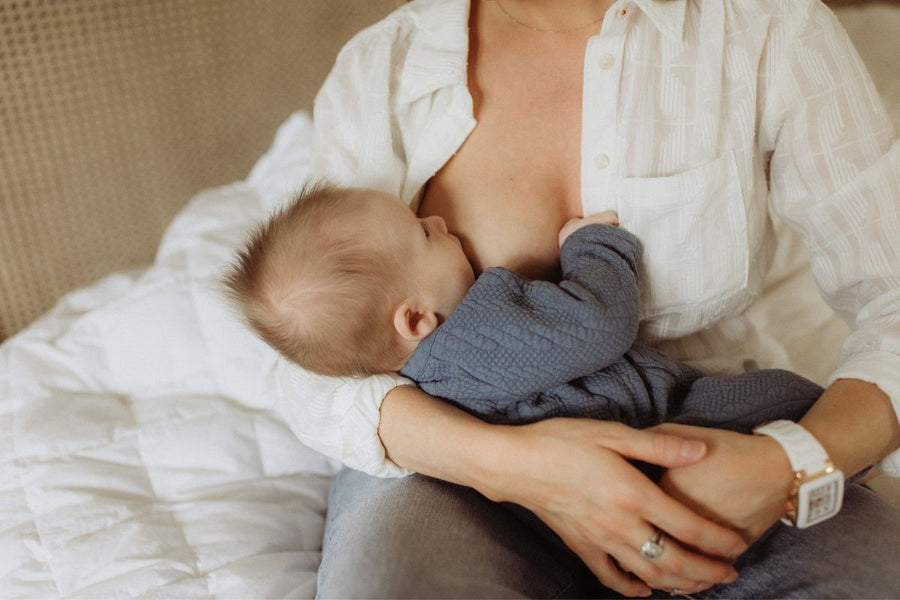 A mother sitting on a bed and breastfeeding her baby, providing closeness and nourishment