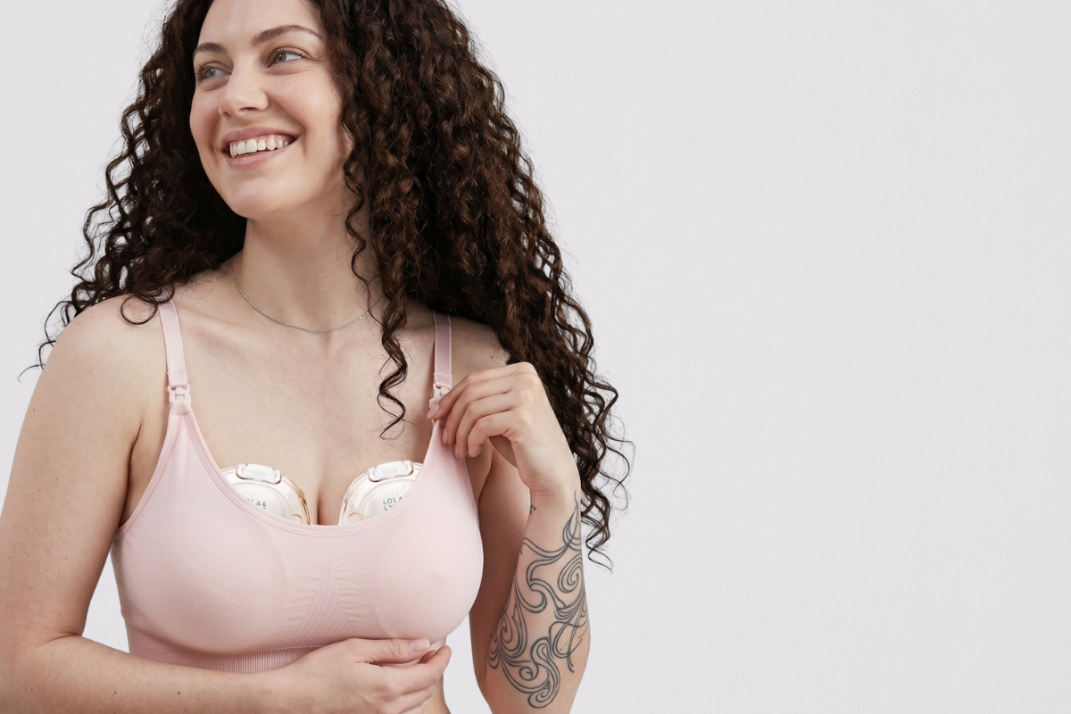 A woman wearing a wearable breast pump on both breasts.