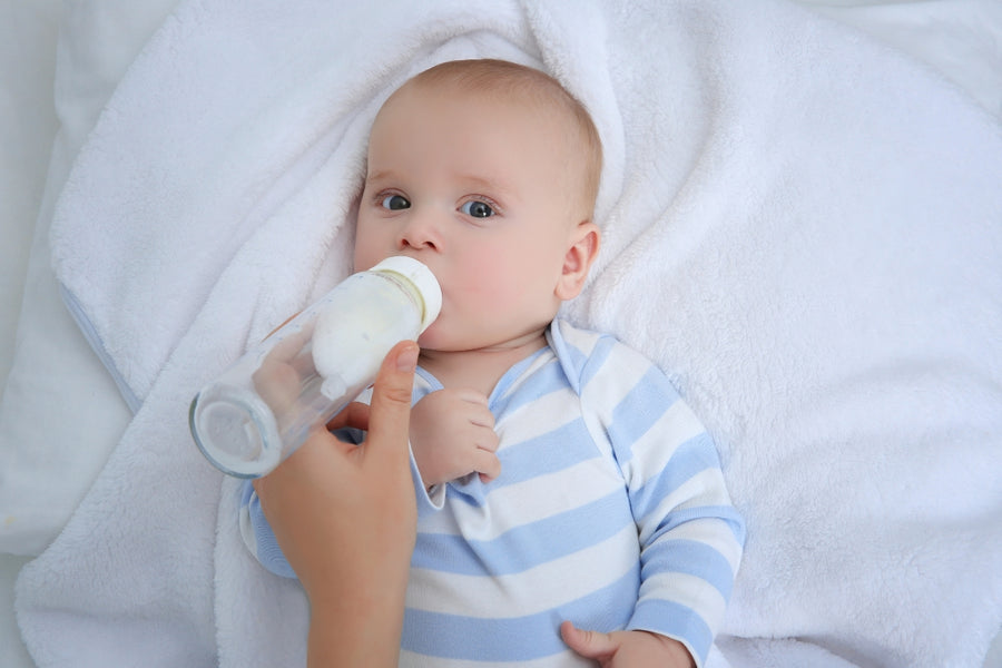 Baby lying down while drinking from a breastfeeding bottle with a natural flow, mimicking the breastfeeding experience.