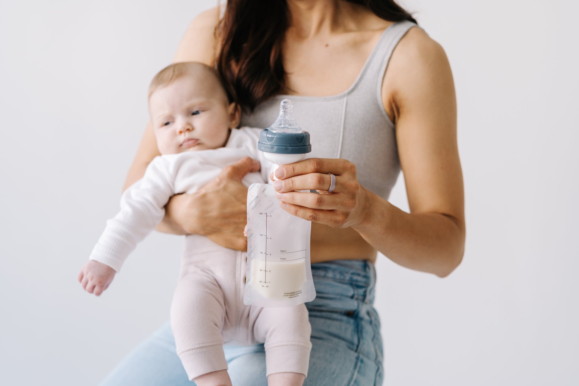 Mother holding her baby close, with a bottle of breast milk 