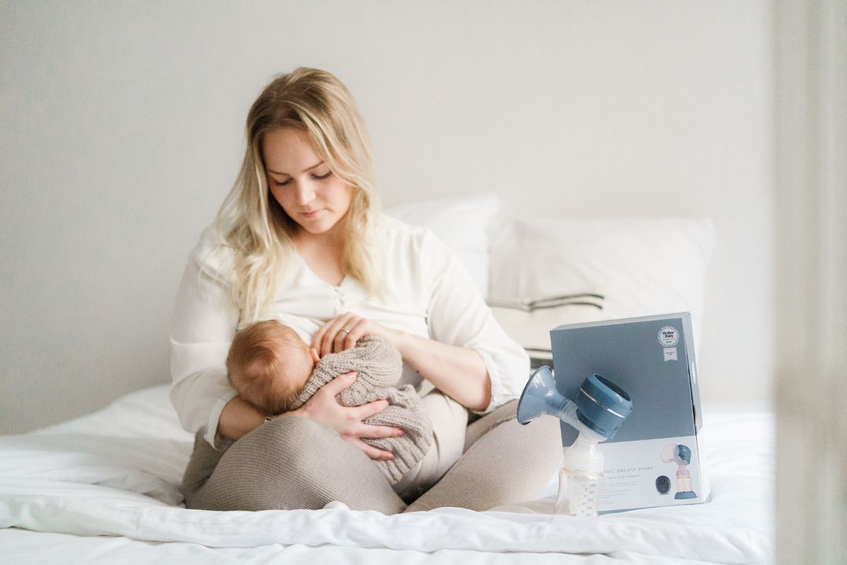 A mother sitting in bed, cradling her baby and breastfeeding with love and care