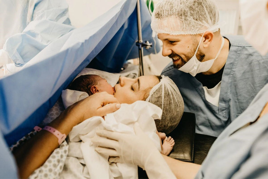  a mother and father lovingly hold their newborn baby in their arms after a c-section delivery
