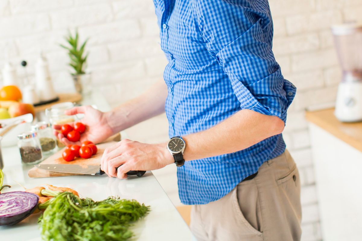 Man in a kitchen cutting cherry tomatoes