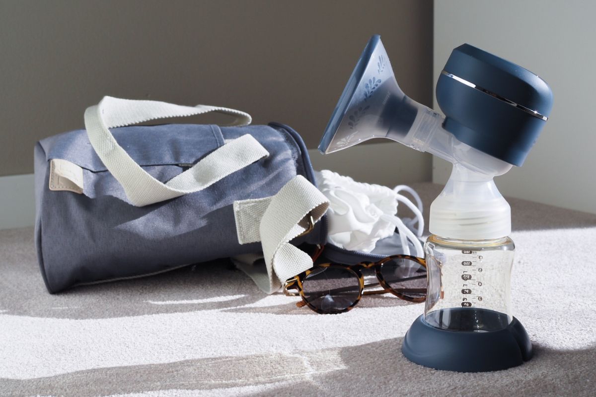 Lola&Lykke Smart Electric Breast Pump in front of a bag and sunglasses