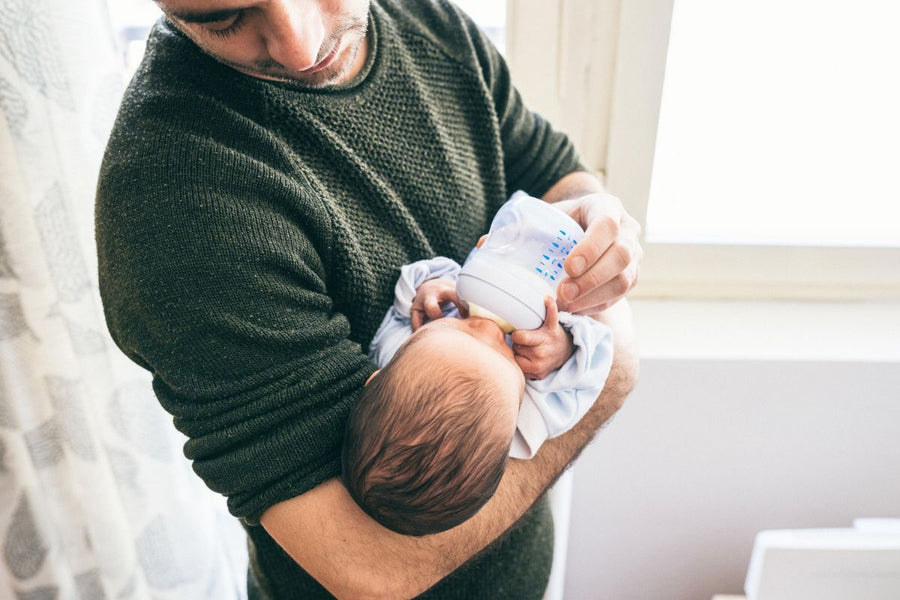 Father holding his baby close, bottle-feeding with love and warmth