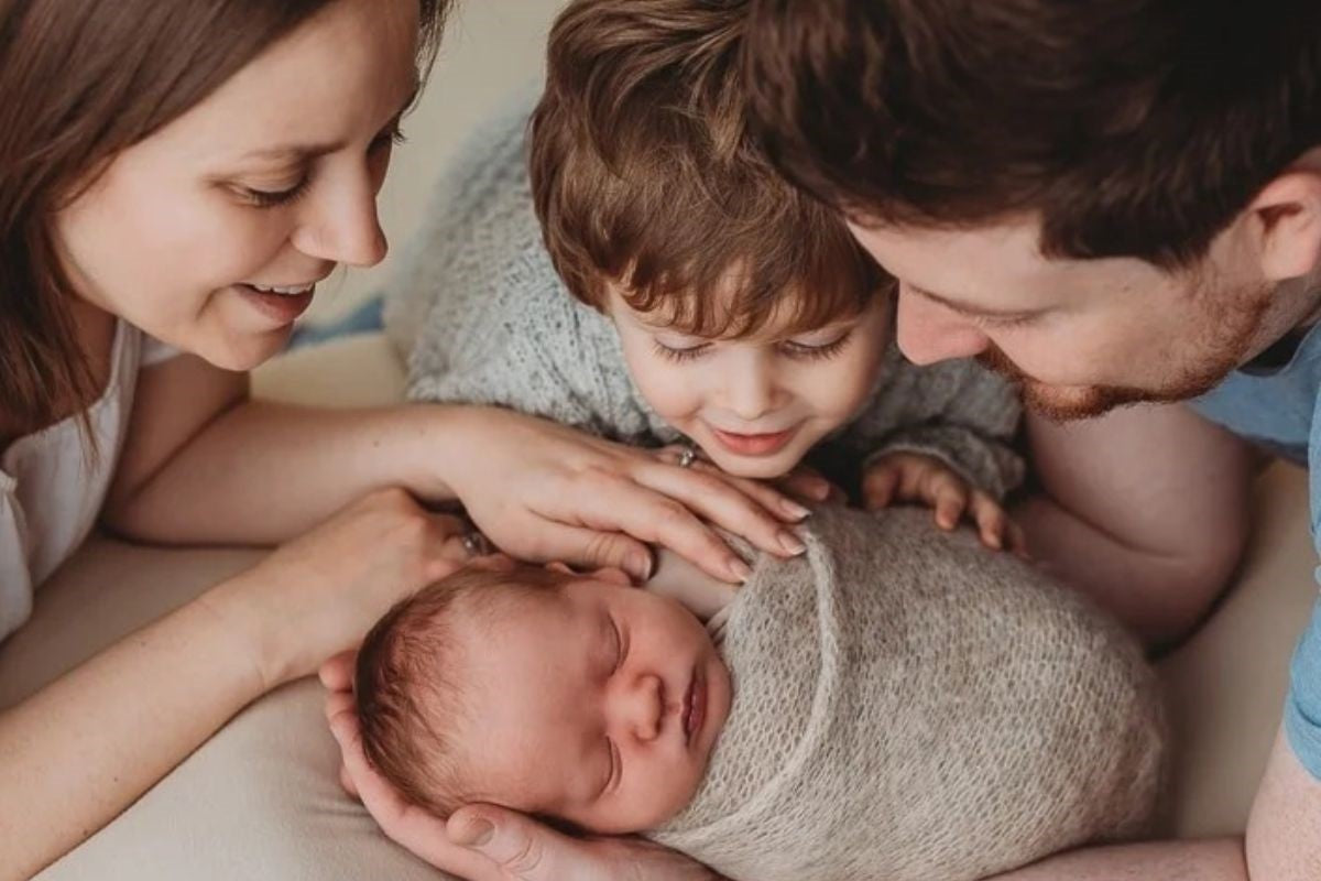 A joyful moment of a mother, father, and their son embracing their newborn baby with love