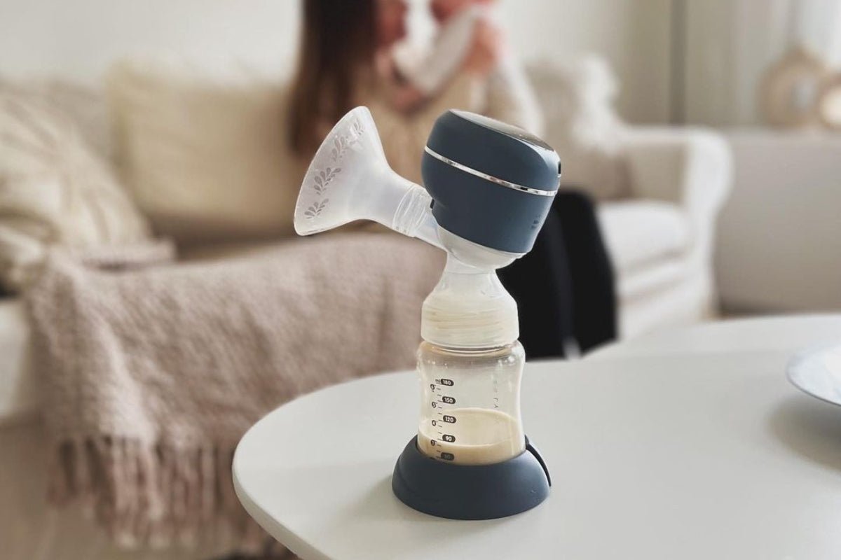 Lola&Lykke Smart Electric Breast Pump showcased alongside a mother lying on a couch with her baby in the background