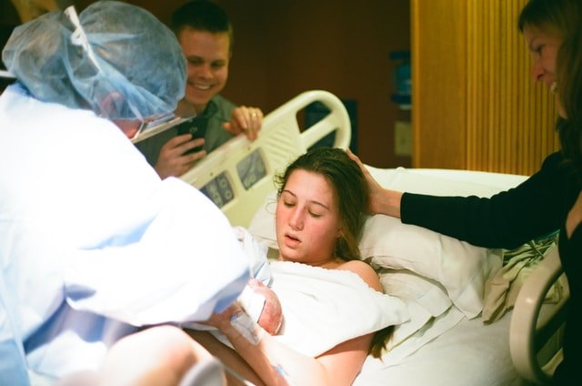 a mother laying in a hospital bed and holding her baby after giving birth