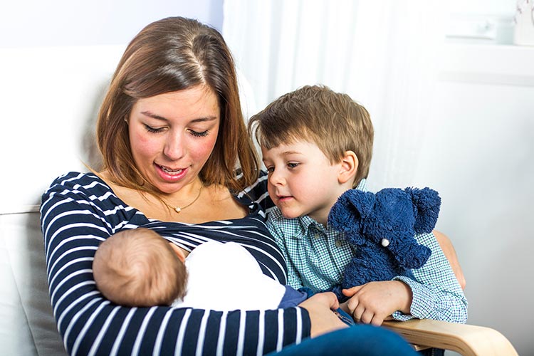 A todler reacting to mother breastfeeding baby