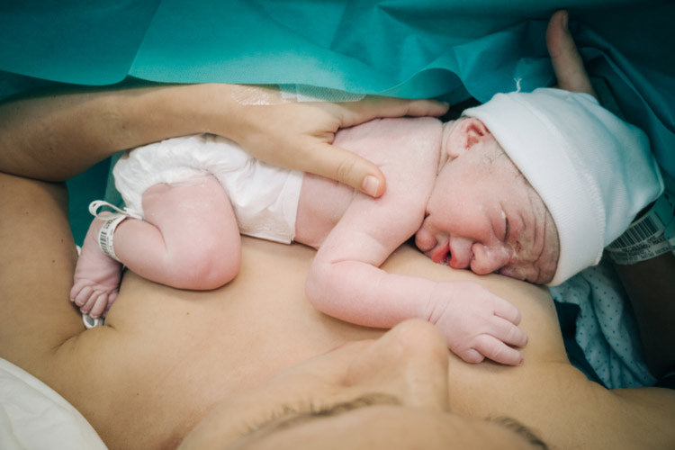 A mother cradling her baby against her breast after a C-section delivery