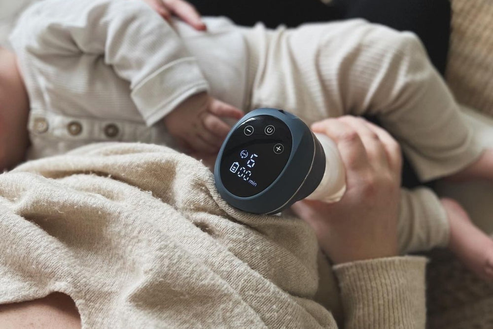 Close-up of a mother breastfeeding her baby while using the Lola&Lykke Smart Electric Breast Pump.