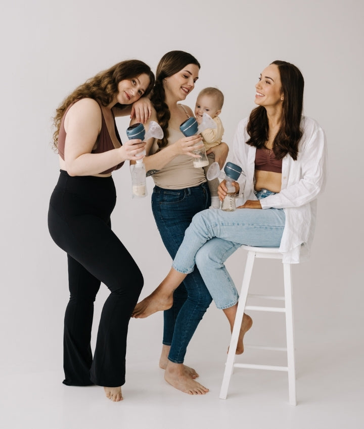 Three women with a baby and breast pumps on a white background