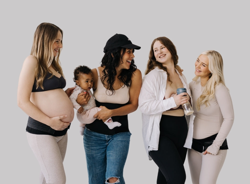 Four women, including a pregnant one, standing together against a plain background, all using maternity support belts.